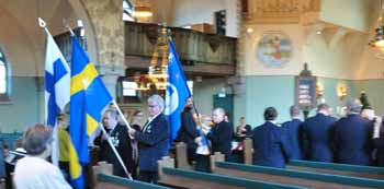 Fanor och fanbärare marschear ut ur kyrkan